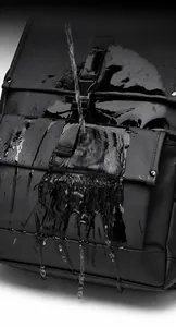 Waterproof detail of black outdoor backpack showing water droplets on matte fabric