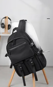 Detail of multi-pocket black nylon backpack featuring buckles and adjustable straps