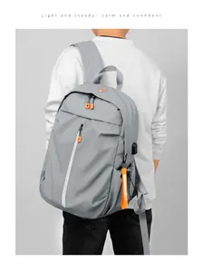 Detail of grey waterproof backpack showing side USB charging port and orange zip accents