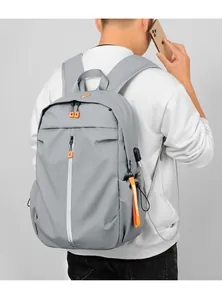 Detail of grey tech backpack with USB port, orange zipper pulls and padded straps