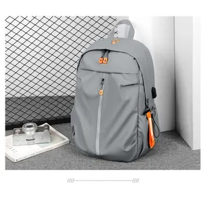 Detail of gray waterproof backpack with orange zipper pull and external USB charging port