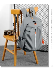 Close-up of grey waterproof backpack with orange zipper details on a wooden chair