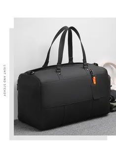 Detail of matte black waterproof travel bag with reinforced handles and orange luggage tag