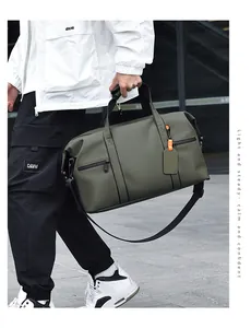 Detail of olive green travel bag with black handles and orange luggage tag accents