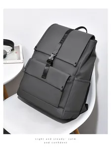 Detail of grey matte backpack with black vertical buckle strap resting on white chair