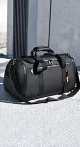 Détail d'un sac de voyage noir avec poignées renforcées et étiquette orange élégante