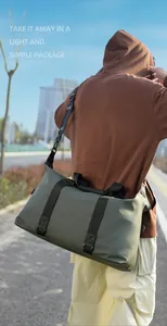Borsa da viaggio verde oliva con tracolle nere portata da una persona all'aperto