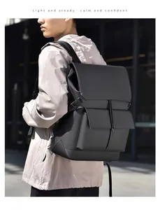 Detail view of a black geometric backpack with top flap and front utility pockets