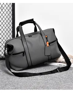Detail view of large dark grey travel bag with orange zipper pull and adjustable shoulder strap