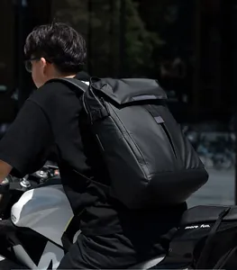 Waterproof black travel backpack shown on a motorcyclist during an outdoor commute