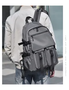 Detail of dark grey multi-pocket tactical backpack on a person in urban setting