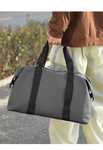 Dettaglio borsa da viaggio grigia con manici neri rinforzati e finitura opaca