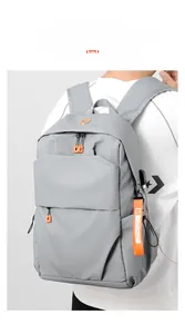 Close-up of gray waterproof backpack featuring USB charging port and orange zip detail