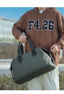 Grande borsa da viaggio verde militare tenuta da un modello in un contesto urbano