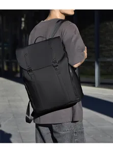 Détail du tissu imperméable noir mat et des boucles de fermeture sur un sac à dos pour homme