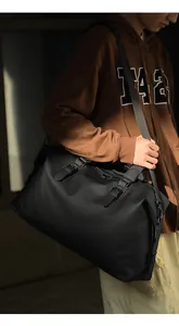 Dettaglio di una grande borsa da viaggio in nylon nero con fibbie in un ambiente all'aperto