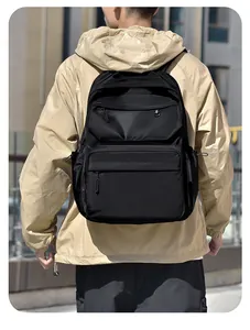Rear view of model wearing a large black waterproof travel backpack with multiple pockets