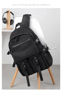 Detailed view of black multi-pocket backpack with durable buckles on a chair