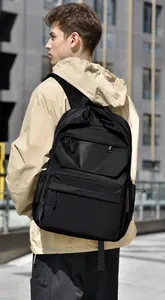 Outdoor shot showing a black waterproof travel backpack with multi-layer zipper storage