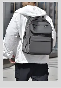 Rear view of a man wearing a grey waterproof travel backpack in a modern urban city