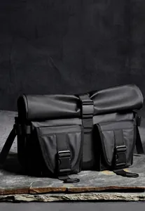 Close-up of waterproof black messenger bag with flap magnetic buckle and dual front pockets