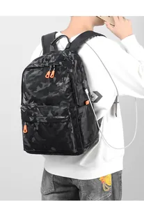Détail du sac à dos camouflage noir montrant le port USB et la fermeture éclair orange