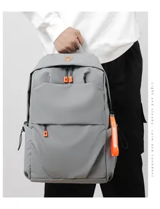 Detail of grey waterproof backpack featuring vibrant orange zippers and sturdy top handle