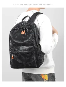 Détail du port de charge USB et de la fermeture orange sur le sac à dos camouflage