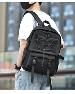 Tactical black backpack detail showing side adjustment buckles and mesh pocket in urban setting