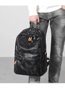 Détail du sac à dos camouflage noir avec fermetures orange et port de charge USB