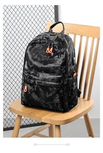 Détail du sac à dos camouflage avec fermetures orange et port USB sur un siège