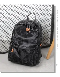 Détail du sac à dos camouflage noir montrant le port USB et les zips orange vifs