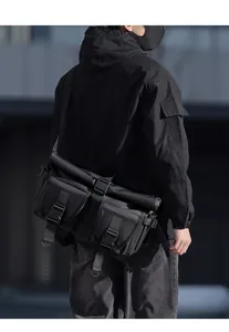 Close-up of black urban techwear messenger bag featuring roll-top and tactical pockets