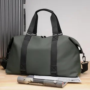 Grande borsa da viaggio verde scuro con manici e tracolla su valigia argento