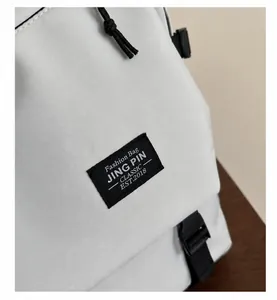 Detail of white fabric backpack showing black drawstring and plastic buckle closure