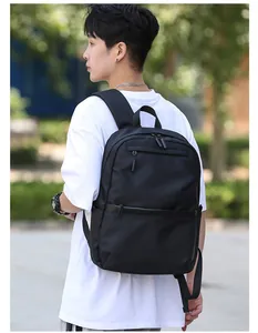 Outdoor shot of a black minimalist large capacity backpack on a model in white T-shirt