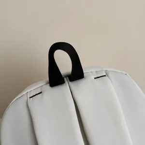 Detail of the reinforced black strap handle and wide white shoulder straps on the backpack