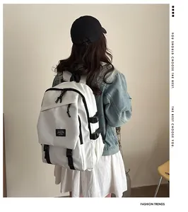 Detail view of white backpack featuring black buckle straps and fashion logo patch