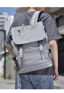 Detail of grey outdoor backpack with flap cover, dual buckles and orange zipper accents