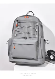 Grey nylon backpack with orange zippers, mesh front pocket and bungee cord details