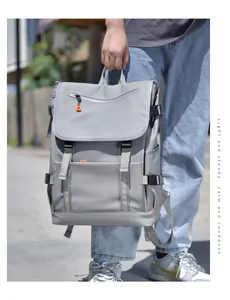 Outdoor street view of a person holding a large gray backpack with orange zippers
