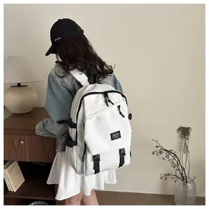 Rear view of a model wearing the large capacity white nylon backpack with black trim