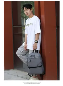 Outdoor lifestyle shot of a grey multi-zipper backpack styled with casual streetwear