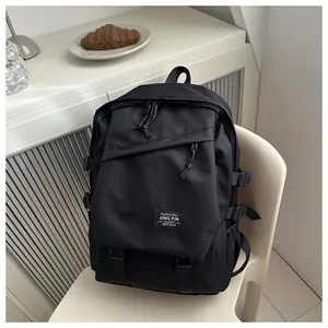 Detail view of large black canvas backpack with multi-layer zippers on a beige chair