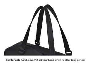 Close-up of reinforced double handles with fine stitching on a black travel duffel bag