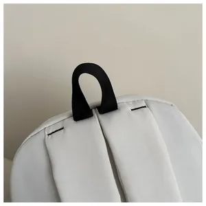 Close-up of durable black nylon handle and reinforced stitching on a white backpack