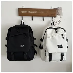 Detail view of black and white nylon backpacks with buckle straps and minimalist labels