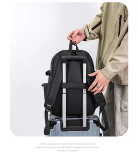 Détail du sac à dos avec sangle de bagage fixée à la poignée d'une valise argentée