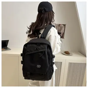 Detail of black waterproof nylon backpack featuring multi-pocket design and front woven label