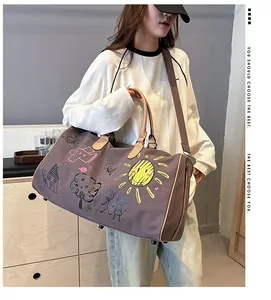 Détail d'un sac de voyage en toile avec graffitis et poignées en cuir sur sweat blanc